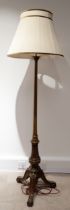 An Edwardian walnut standard lamp, with turned column to carved downswept and scroll footed tripo...