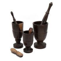 Three turned wooden goblet shaped  mortars with four various turned wooden pestles. (7).