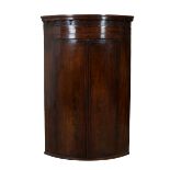 Georgian mahogany bow fronted corner cupboard with ebony and boxwood stringing, castellated pedim...