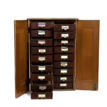 Early 20th Century pine haberdasher's cabinet with lockable panel doors opening to reveal 18 draw...