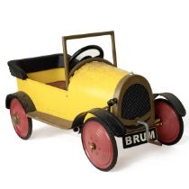 A vintage "Ragdoll Brum 2003" ride-on pedal car in yellow and red with pedals and crank handle, t...
