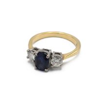 An 18ct yellow gold sapphire and diamond three stone ring, the oval cut sapphire flanked by two r...