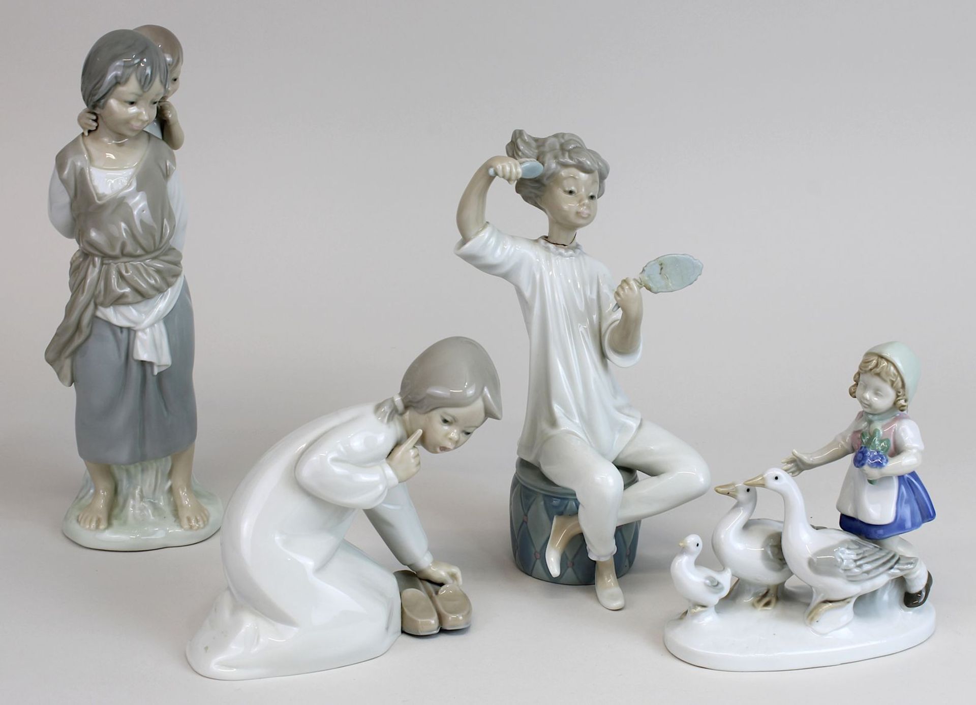 Vier Kinderfiguren, Porzellan, 2. H. 20. Jh., ein auf dem Boden knieendes, nach Schuhe greifendes