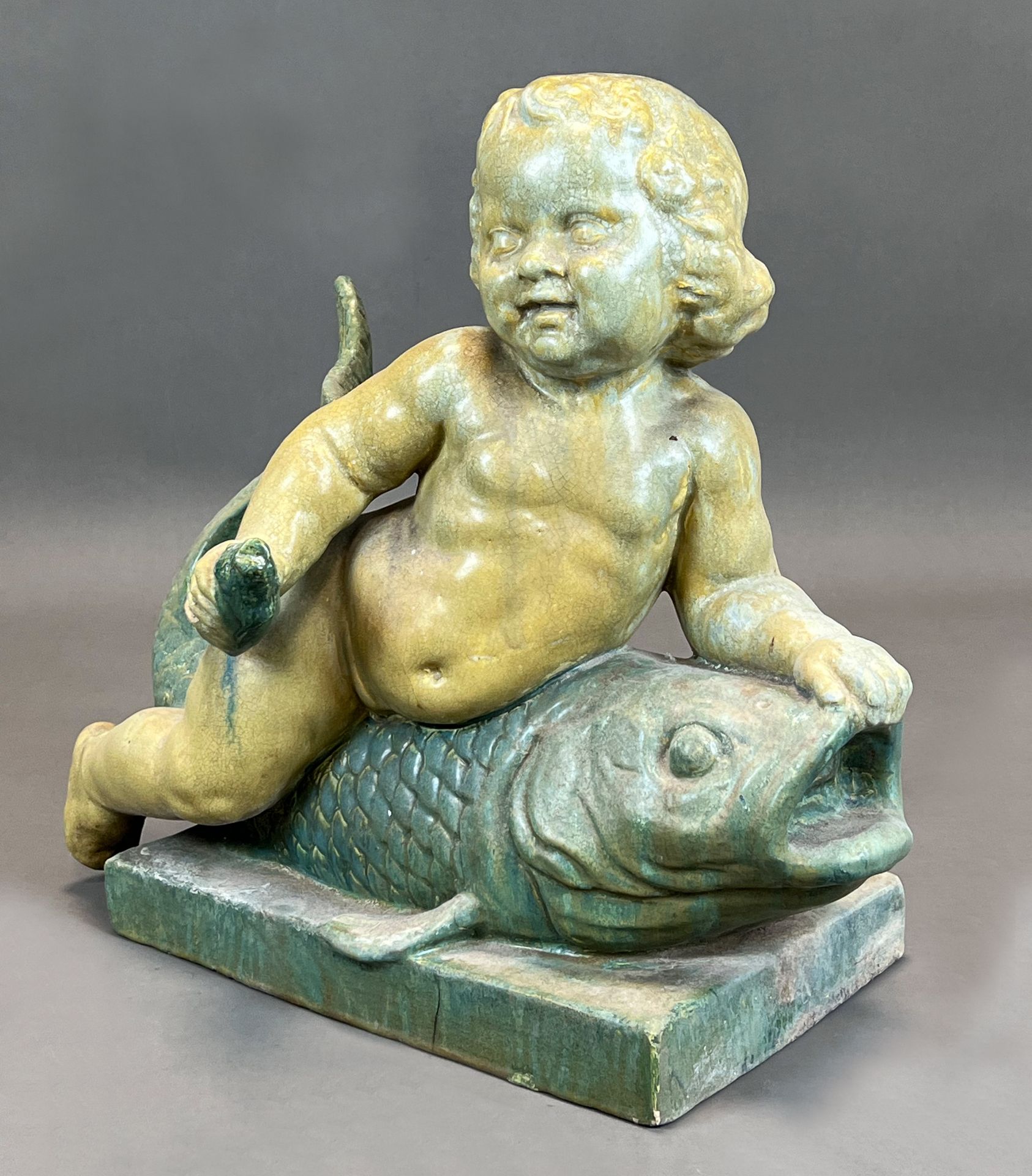 Majolica figure. Putto on a fish. Early 20th century.