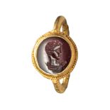 A Roman carnelian intaglio engraved with a bust of Apollo, set in its original 2nd Century AD gold r