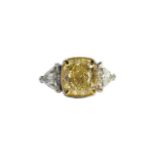 European, Circa 2000, An impressive cushion-shaped yellow diamond and white diamond three-stone ring