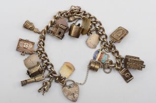A silver heart shaped clasped charm bracelet with souvenir charms, 67gm.