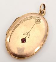 An unmarked gold front and backed oval locket, with red paste stone and chased floral decoration, 40