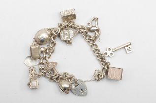 A silver heart shaped clasped charm bracelet with charms, 65gm.