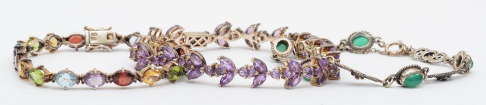 A silver amethyst tennis bracelet, 19.5cm, together with a silver multi gem set example and another,