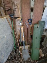 A group of used garden tools to include spades, trimmers and rakes.