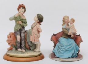 Two 20th century Capodimonte painted porcelain figures, mother and child sitting on a sofa, 17cm