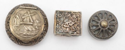 A Dutch silver pill box with embossed foliate scroll and windmill decoration, 4cm, together with two