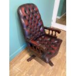 A mid 20th century brown leather Chesterfield swivel office armchair, button back and studded seat