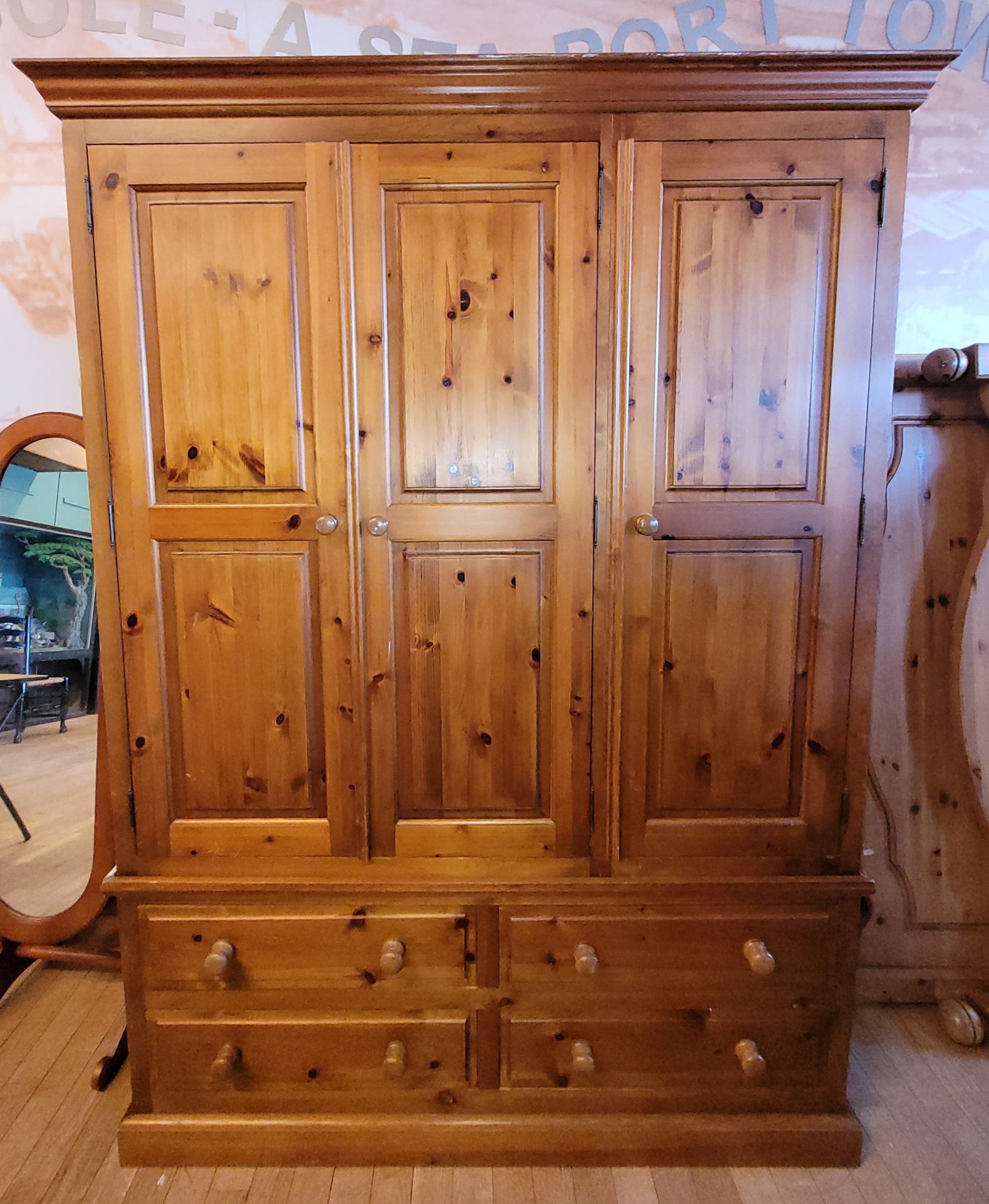 A modern pine triple wardrobe, three panelled doors over four long drawers on a plinth base, W140,