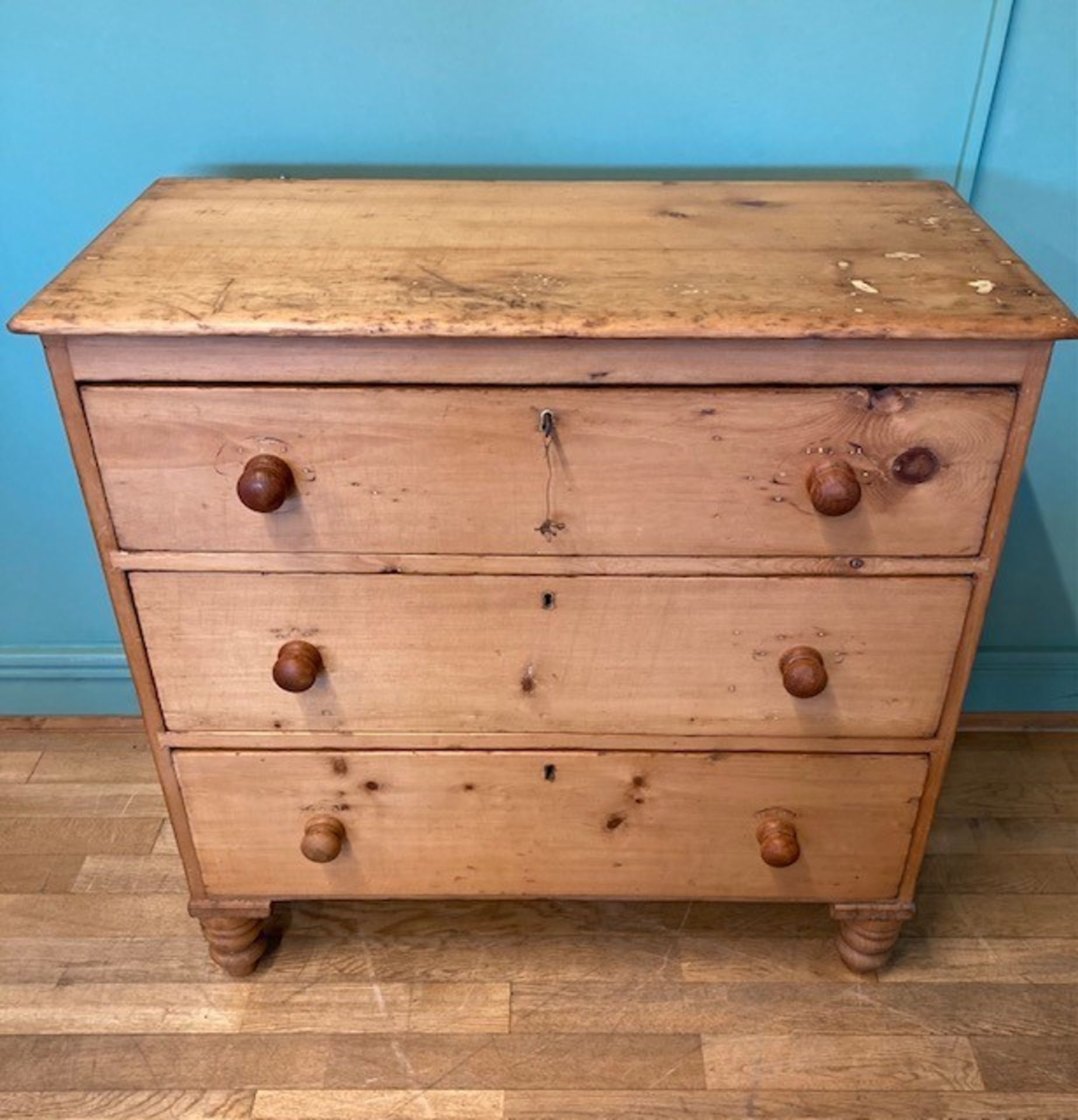 An early 20th century stripped pine chest of drawers, the three graduated drawers with later bun