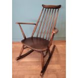 A mid 20th century Ercol rocking armchair, having spindle backrest with shaped top rail and armrests