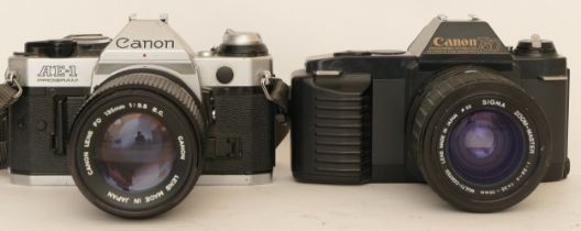 A Canon AE-1 camera with a Canon FD 135mm 1:3.5 lens and a Canon T50 with a Sigma 1:2.8-4 f=35-