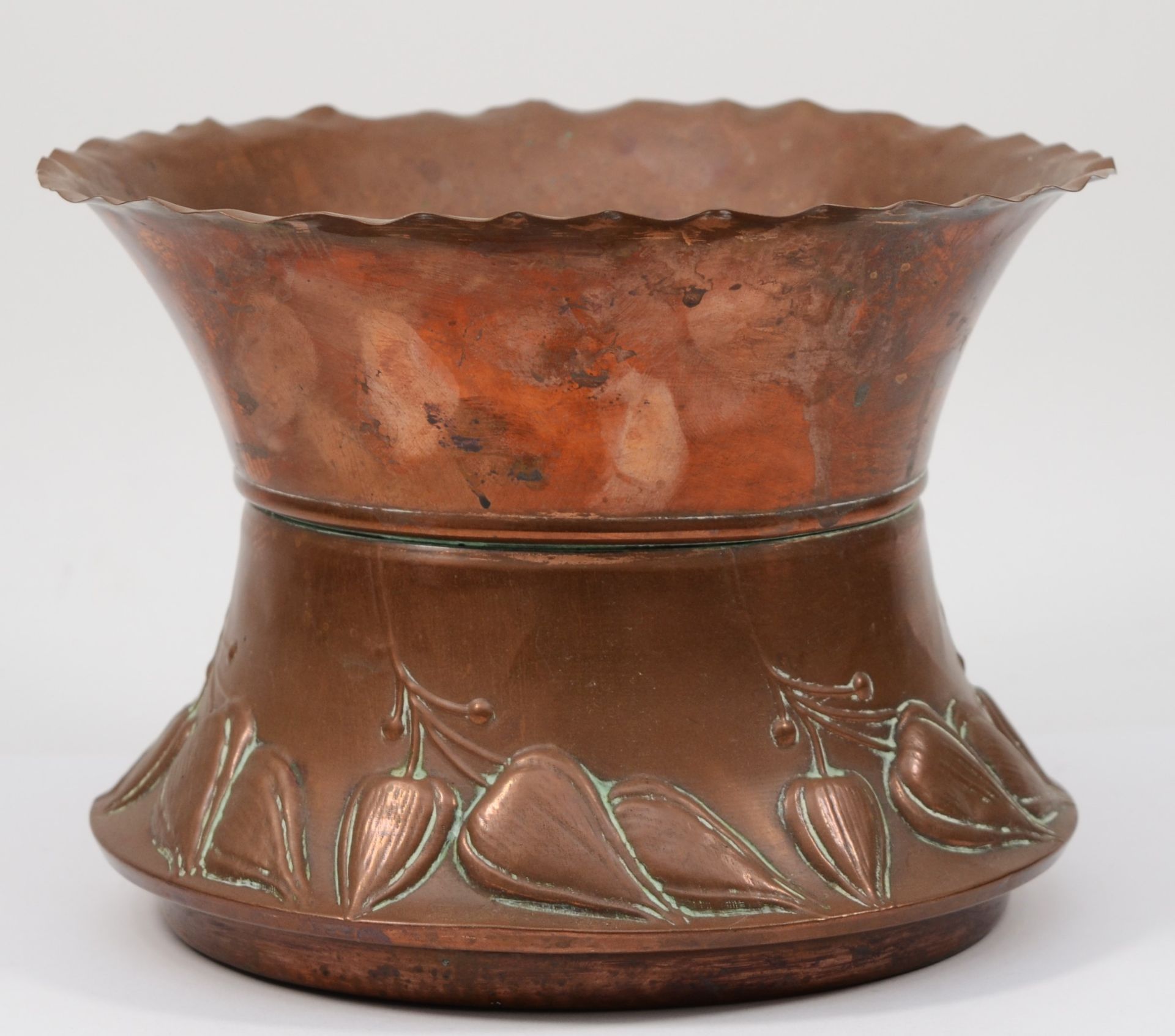 An early 20th century hammered copper waisted cache pot/jardinière, with crimped rim and stylised