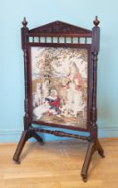An Edwardian carved mahogany framed embroidered fire screen, with twin reeded supports raised on out
