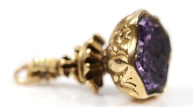 A Victorian unmarked gold cased amethyst seal, with embossed floral decoration, shield shaped