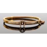 A Victorian 15ct gold horseshoe bangle, set with seed pearls, bead border and safety chain, 59mm,