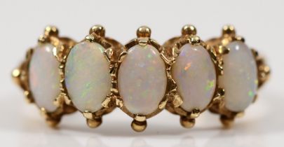 A 9ct gold five stone opal dress ring, with pierced scrolling shoulders, the opals showing flashes