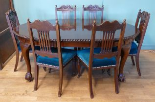 An early 20th century mahogany wind out extending dining table with carved moulding, raised on