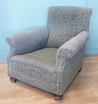 An early 20th century Howard style deep seated armchair, upholstered in a green floral fabric,