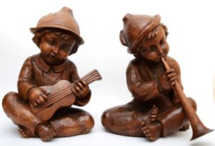 A rare pair of carved wood Hummel figures, presumed ex shop display, of seated boys playing