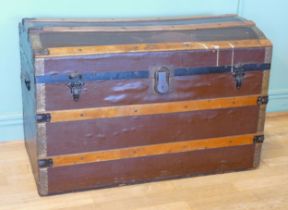 An early 20th century dome topped twin handled trunk, with gilt brass mounts, the hinged lid opening