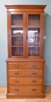 An Edwardian oak twin door glazed bookcase, opening to reveal adjustable shelves above a chest of