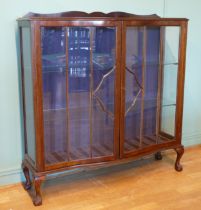 An Edwardian mahogany display cabinet, having two glazed doors of serpentine form opening to