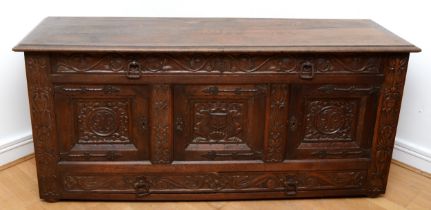 A 19th century heavily carved oak coffer, with two drawers above three cupboard doors, the central