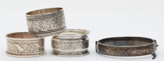 Three napkin rings to include a Victorian example with floral decoration, London 1896, together with