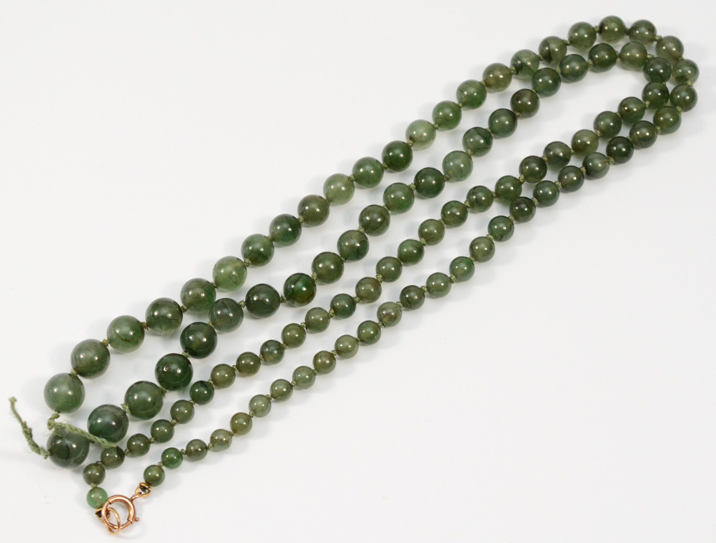 A gold clasped green hard stone graduating beaded necklace, 79cm.