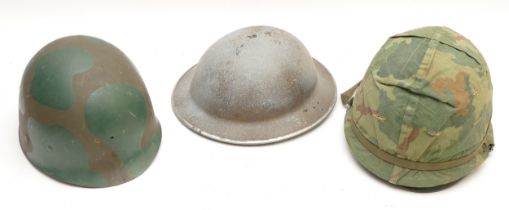 A British WWII steel helmet, an Army issue steel helmet with camouflage cover and Ground Troops