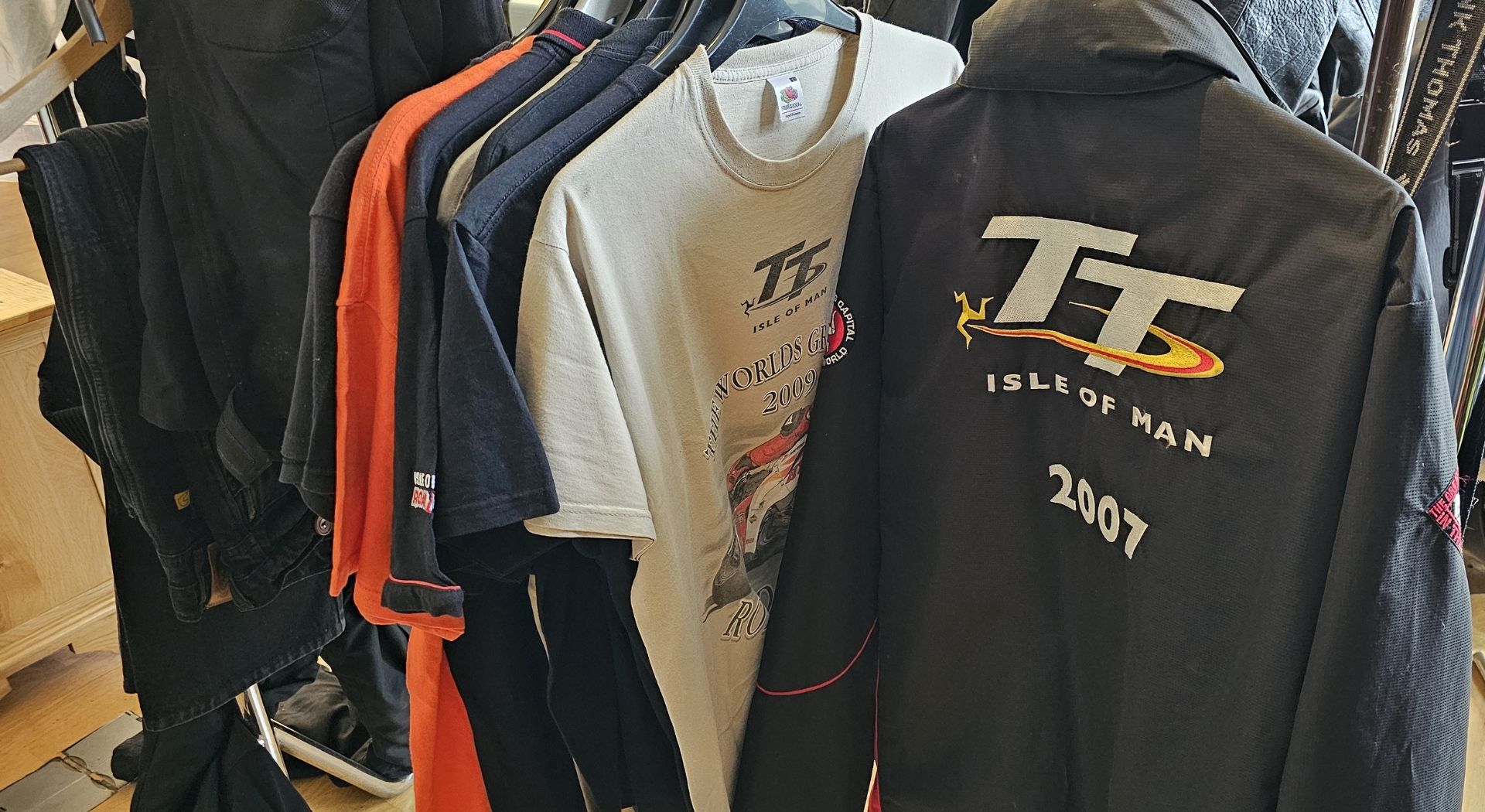 An Isle of Man 2007 TT jacket, size XL, 10 Isle of Man tee shirts and 3 pairs of trousers