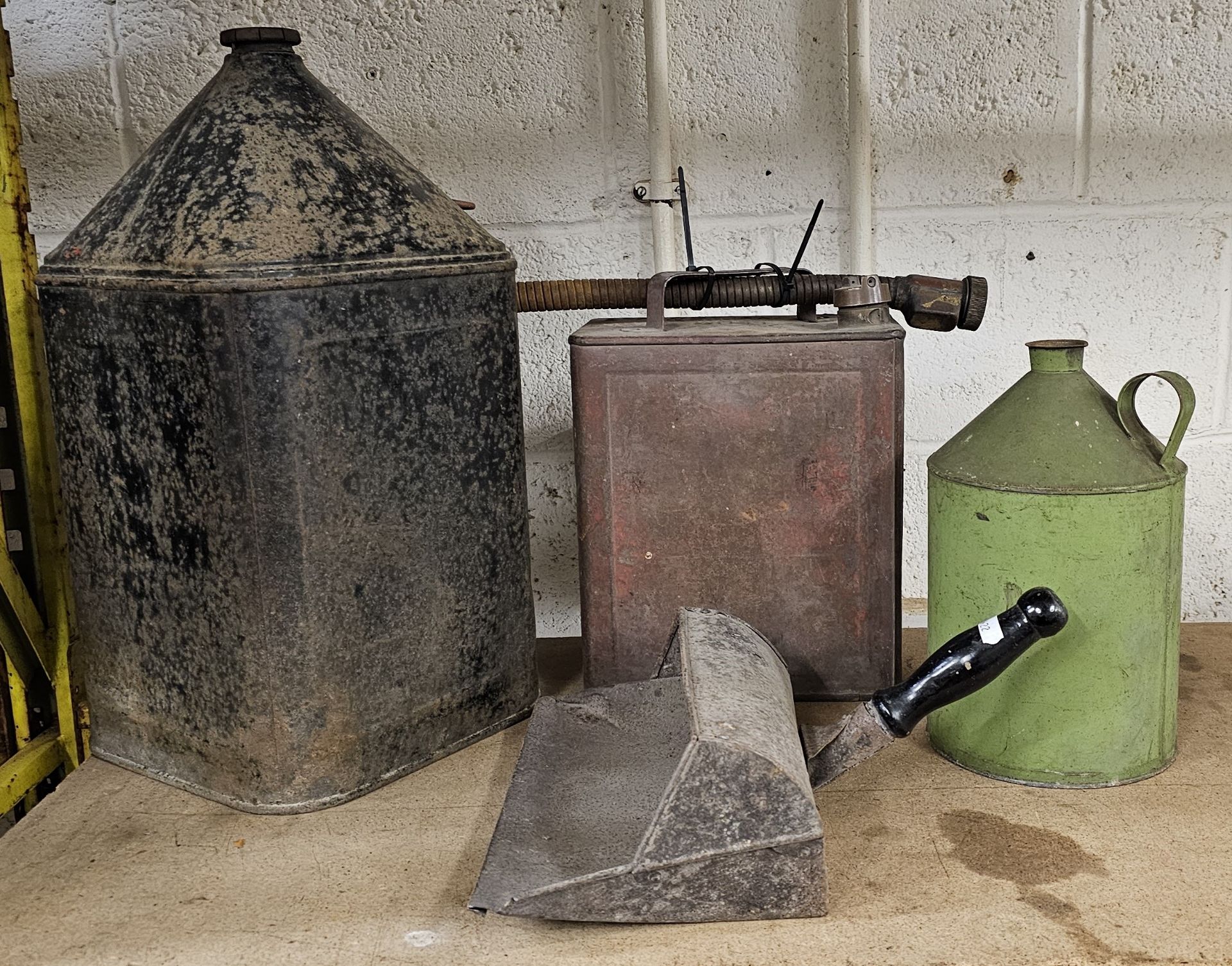 A 5 gallon pyramid can, cap, a 2 gallon petrol can, cap and pourer, another can and a dustpan.