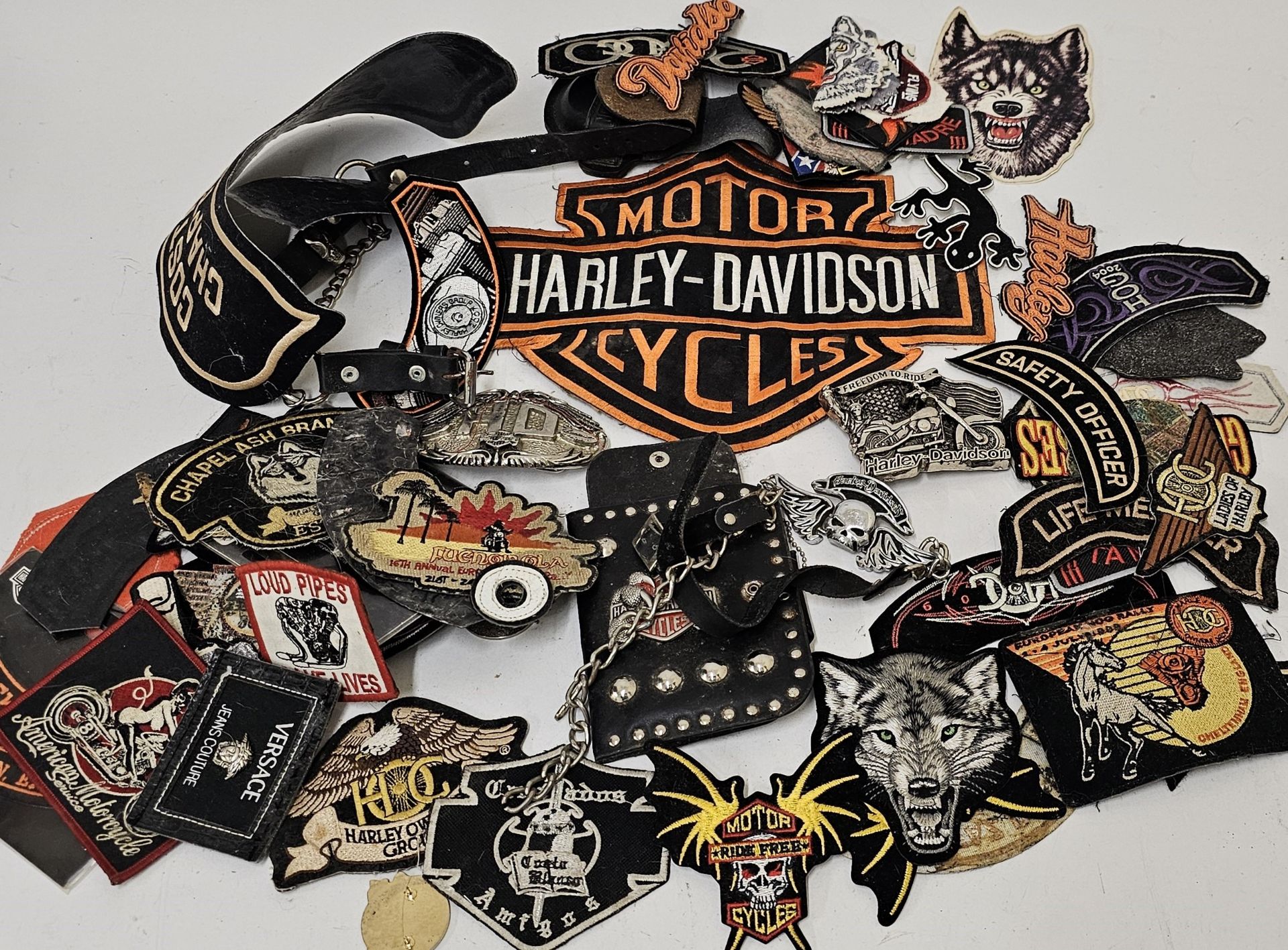 A collection of Harley Davidson ephemera, including two belt buckles a wallet and patches.
