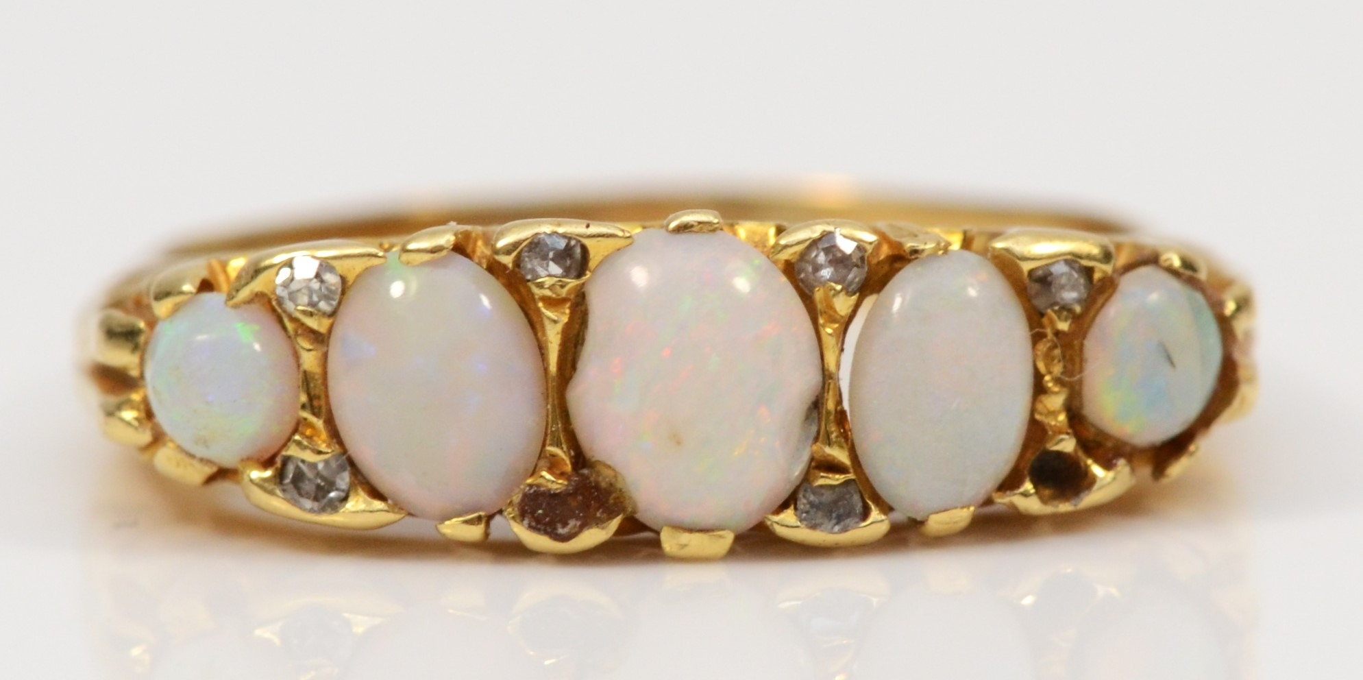 A vintage gold five stone opal dress ring, with eight cut diamond accents, unmarked, flashes of