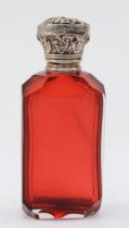 A Victorian silver and red cut glass perfume bottle, unmarked, with embossed foliate scroll