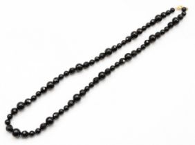 A 14k gold clasped onyx beaded necklace, 66cm.