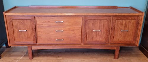 A 1970s teak sideboard, having twin cupboards besides three long drawers and a single drinks