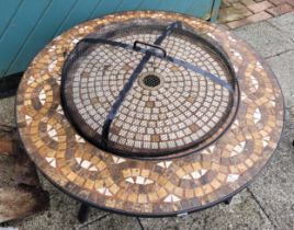 A modern garden side table, painted cast metal with tiled lift off top revealing inbuilt fire pit,
