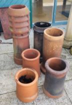 Six early 20th century terracotta chimney pots of various sizes, the largest 91cm tall. (6)