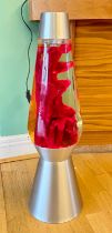 A large lava lamp, brushed aluminium base and top, red wax a clear liquid, measures 68cm in height.