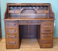 An early 20th century oak tambour twin pedestal writing desk, opening to reveal fitted interior,