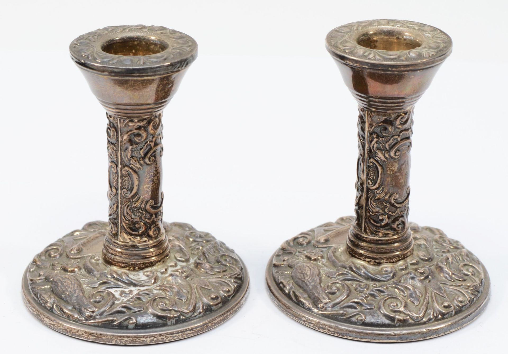 A pair of silver candlesticks, Birmingham 1973, with bird and scroll embossed decoration, 10cm,