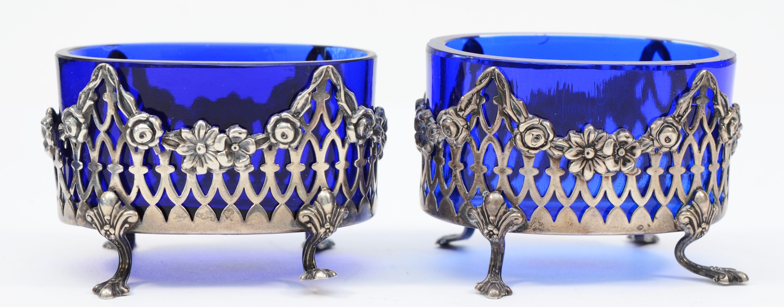 A pair of Sterling Silver pierced salt pots, with blue glass liners, 7.5 x 5cm, 92gms, some splits